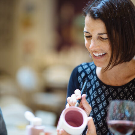 Woman smiling while painting at a small group event at Petroglyph.