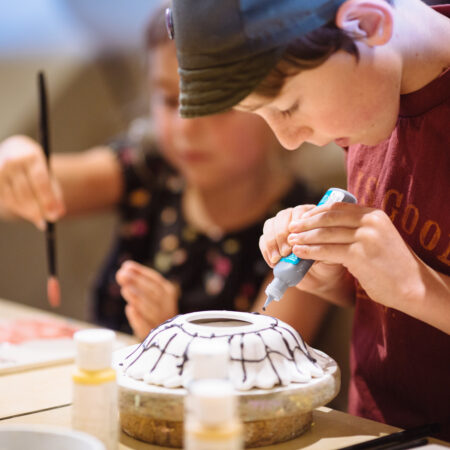Young boy concentrating on painting ceramics at a friends birthday party hosted at Petroglyph.