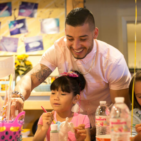 Parent helping children paint their ceramics at a kids birthday party hosted at Petroglyph Sacramento.